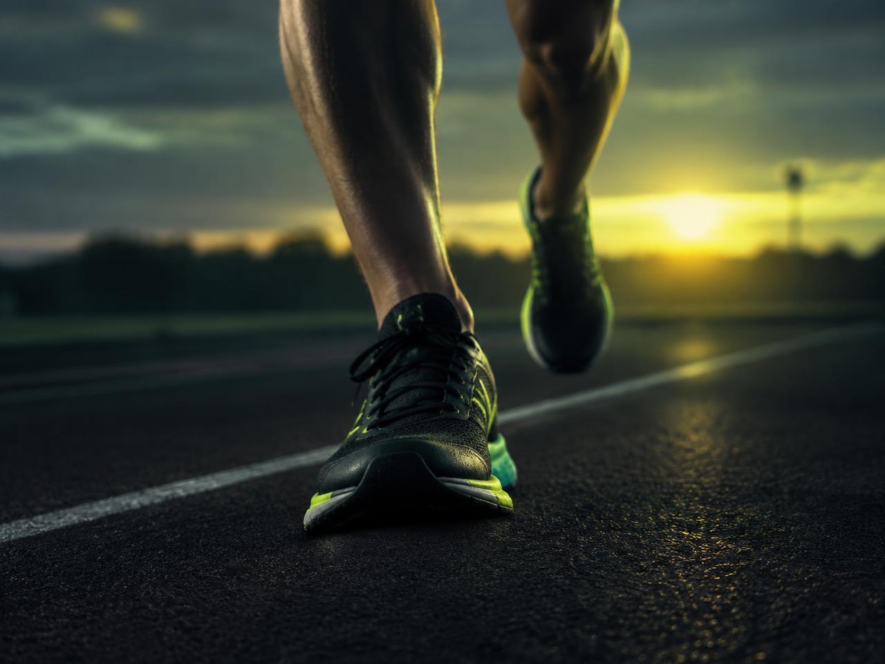 Corredor em pista de atletismo ao amanhecer